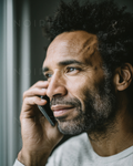 Mann mit lockigem Haar, Bart und Telefon in der Hand, Porträtaufnahme