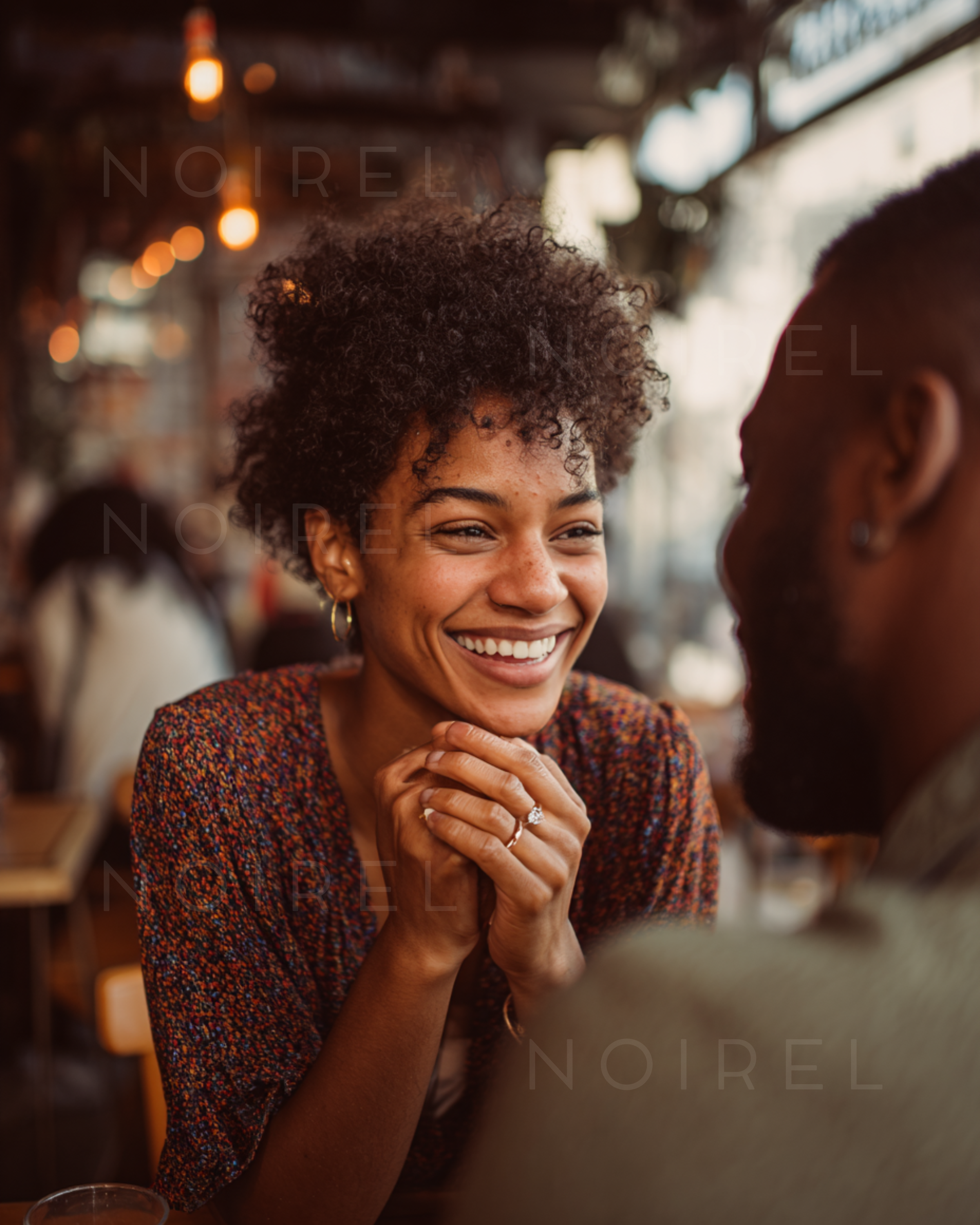 Smiling model with curly hair wearing a maroon speckled knit top