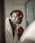 Man applying grooming product to beard, dark skin, close-up grooming action