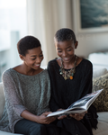 Black textured knit cardigan with long sleeves, worn by a woman seated and reading