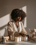 Cream knit cardigan over white top, model with curly hair, hands on table