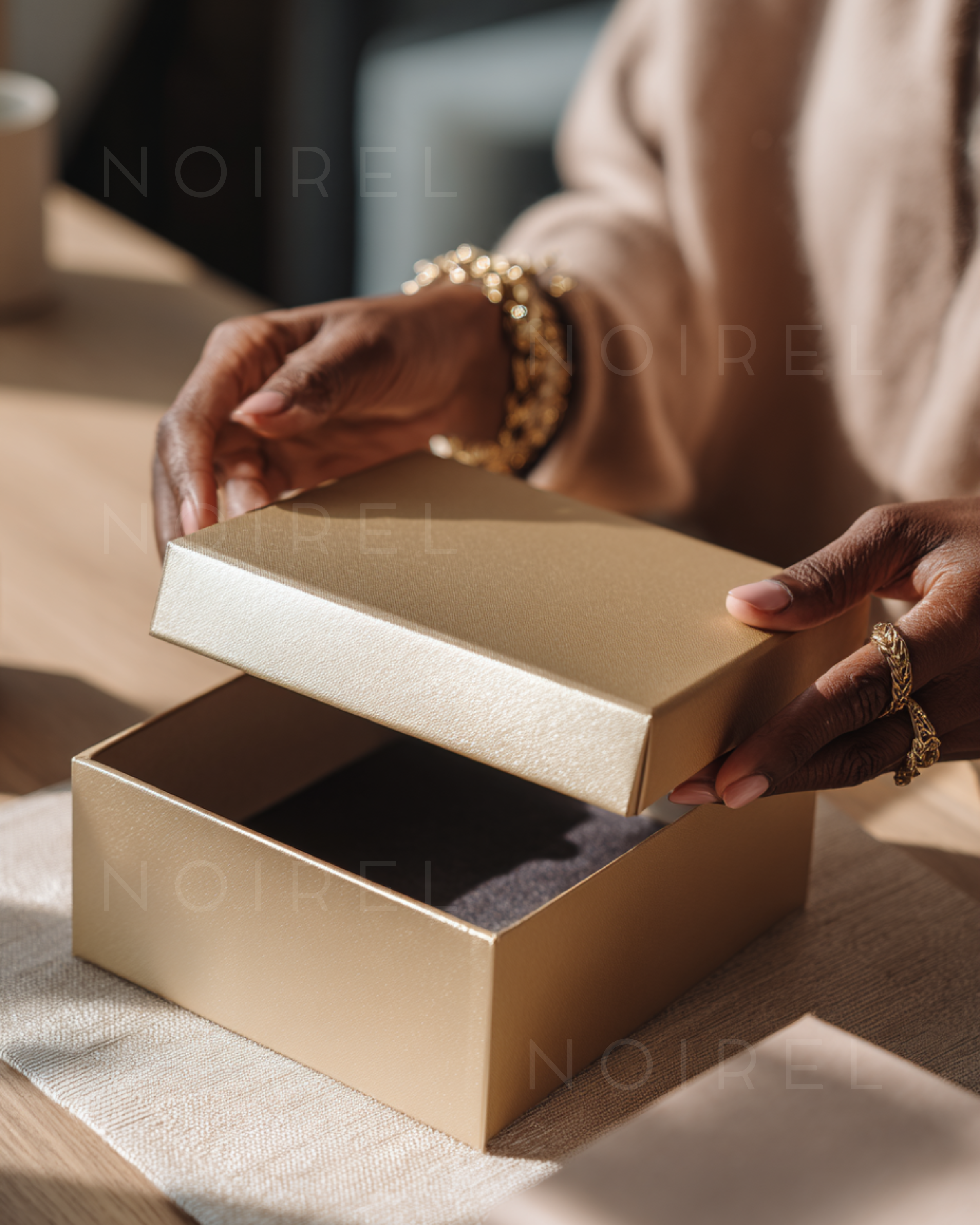 Gold gift box with open lid; hands holding the inner jewelry tray