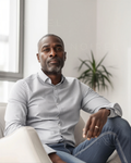 Light gray button-up shirt and blue jeans, seated portrait with folded arms
