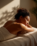 Person with curly hair resting on a towel, arms under head